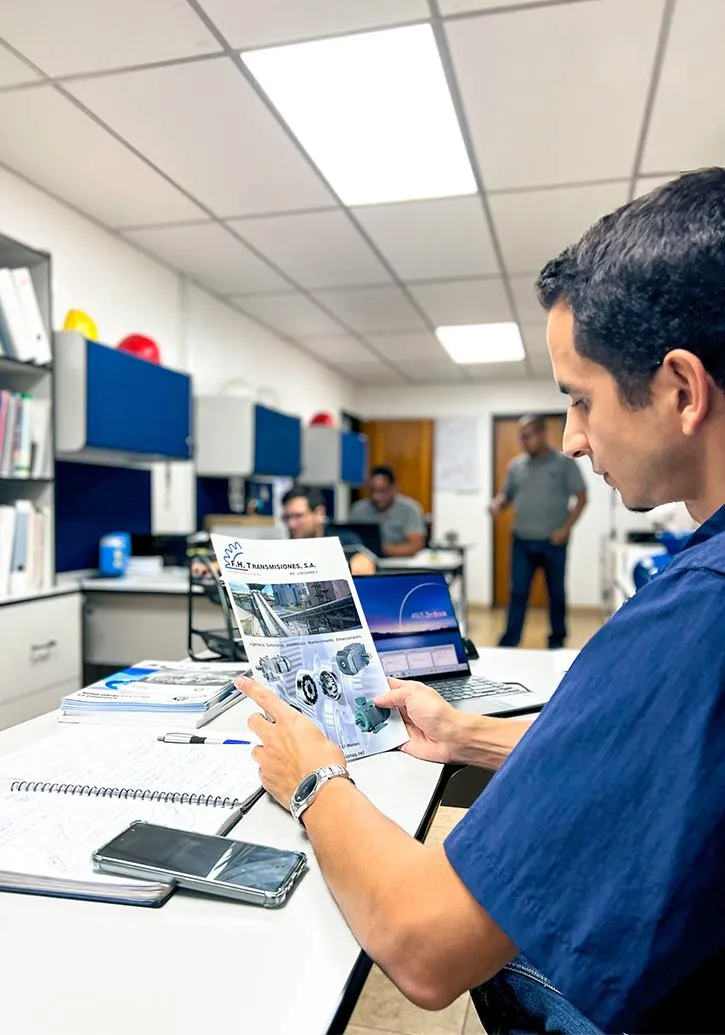 Miembro del equipo comercial de F.H. Transmisiones revisando el catálogo con un cliente